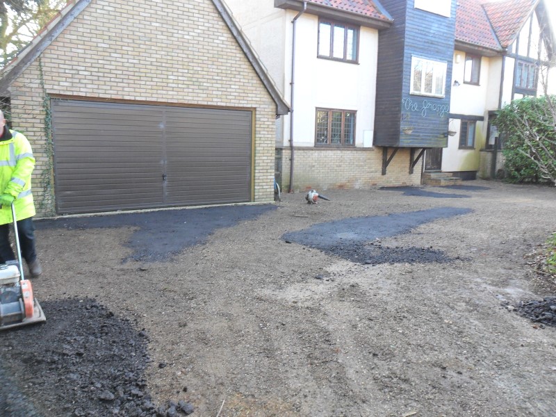 Installing an even base course of tarmac before shingle application.